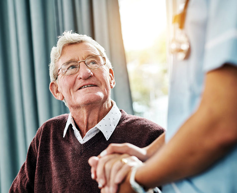 Elderly man looking up at nurse