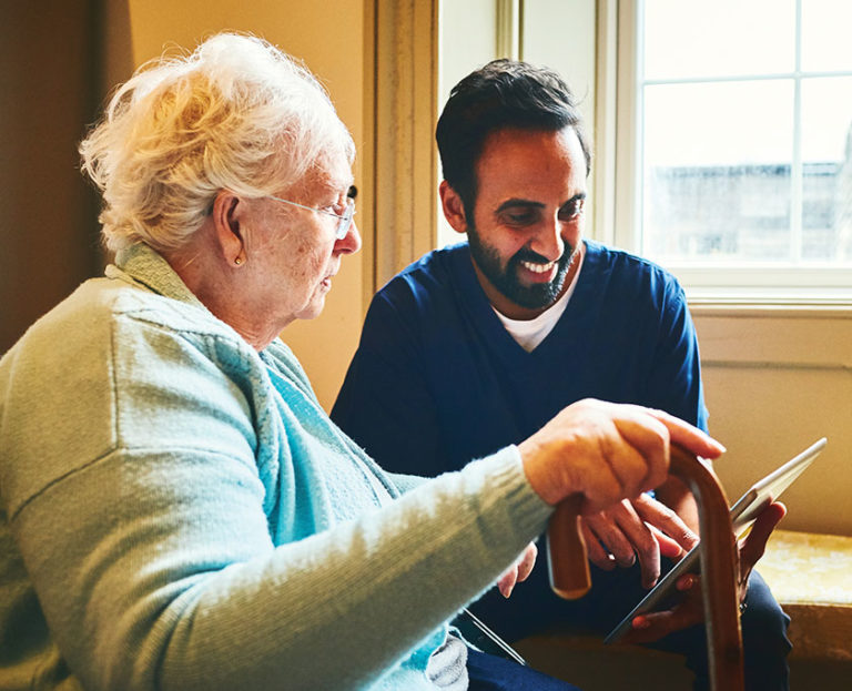 Elderly woman looking at iPad with male nurse